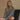 Woman wearing a gray sweater sitting on a chair with a beige background