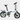 White folding bike on grass with greenery in the background