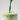Green liquid being poured into a glass with ice on a light gray background