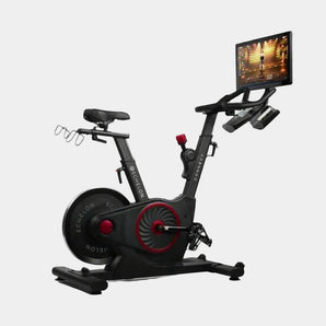 Exercise bike with a screen displaying a workout interface on a grey background