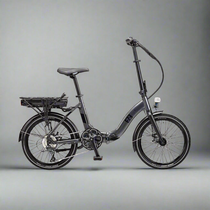 Black folding bicycle on a paved surface with a modern building in the background