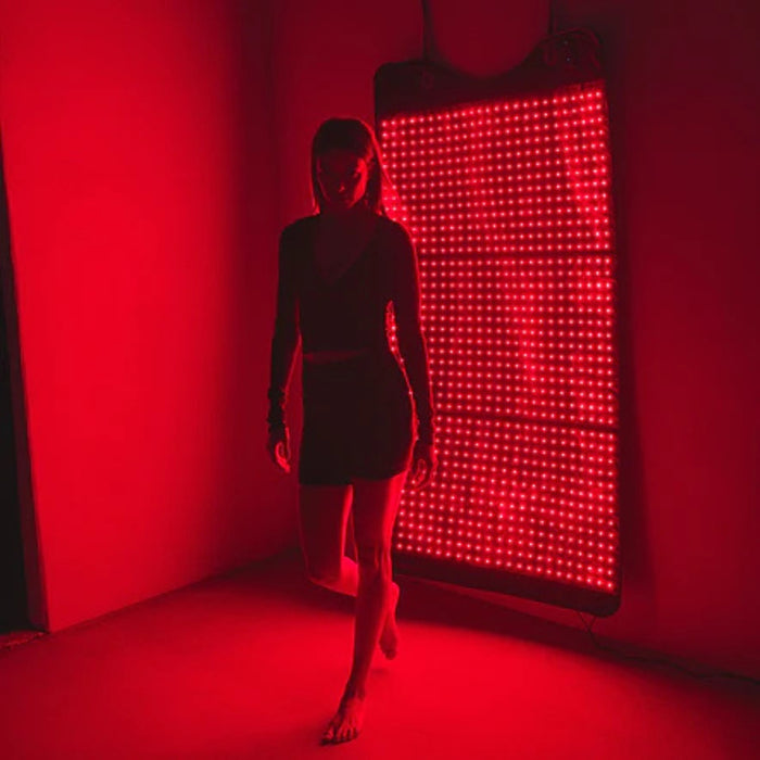 Person standing in a red-lit room with a LED panel on the wall.