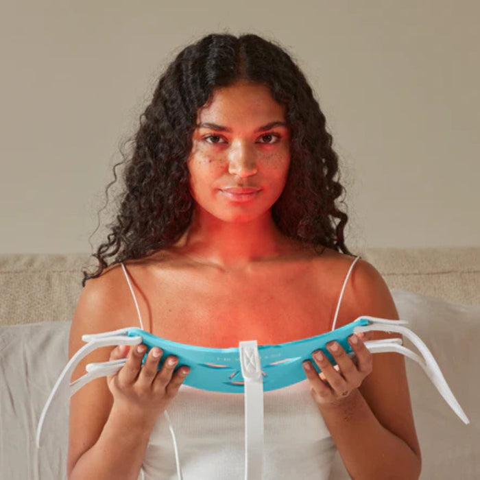 Woman holding a blue device with red light on her face