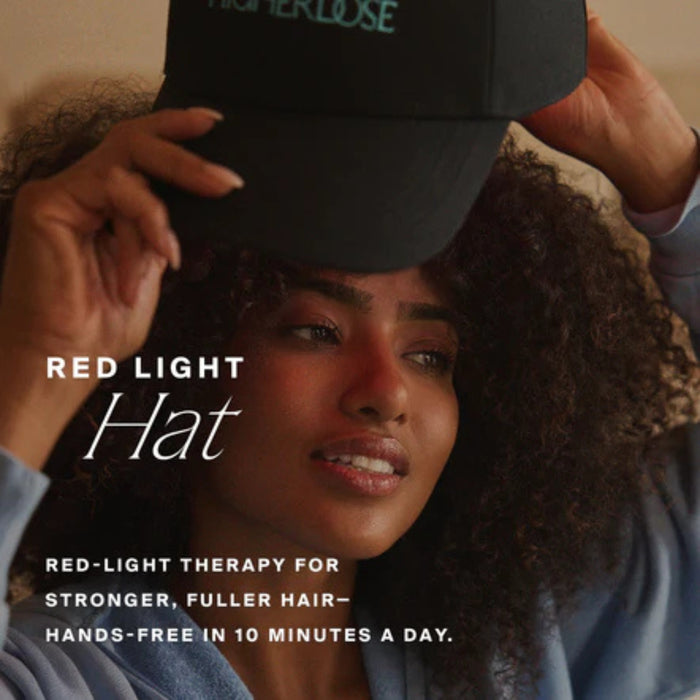 Person wearing a black cap with text about red light therapy for hair growth.