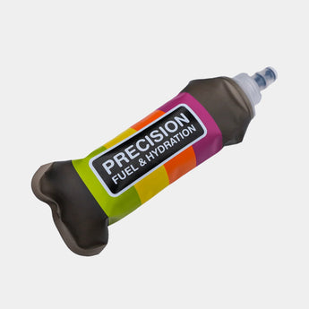 A squeeze bottle of Precision Fuel & Hydration drink mix, filled with a dark brown liquid, featuring a colorful label with green, yellow, orange, and pink stripes on a light gray background.
