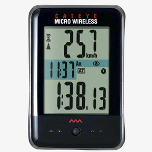 Cateye Micro Wireless Cycle Computer displaying speed and distance information on its digital screen, mounted on a black surface.